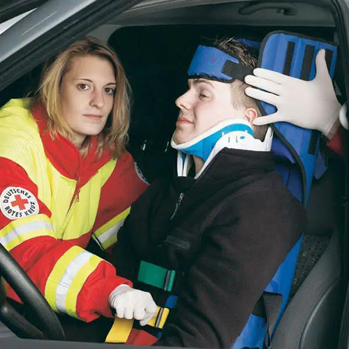 Eine Fachkraft des Roten Kreuzes legt einen blauen Sicherheitsgurt mit dazugehöriger Stützfunktion an eine Person in einem Auto an.jpg